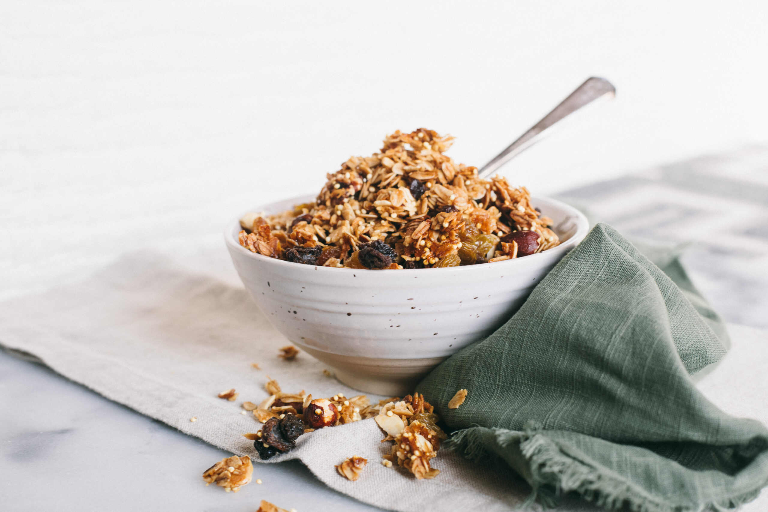 Photo of a bowl of granola on a marble cutting board with a green linen napkin