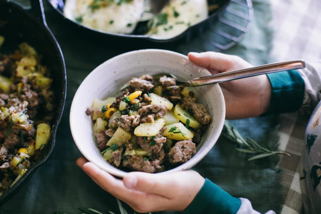 Image of a child holding a bowl in front of a Breakfast Skillet and pam of fried eggs