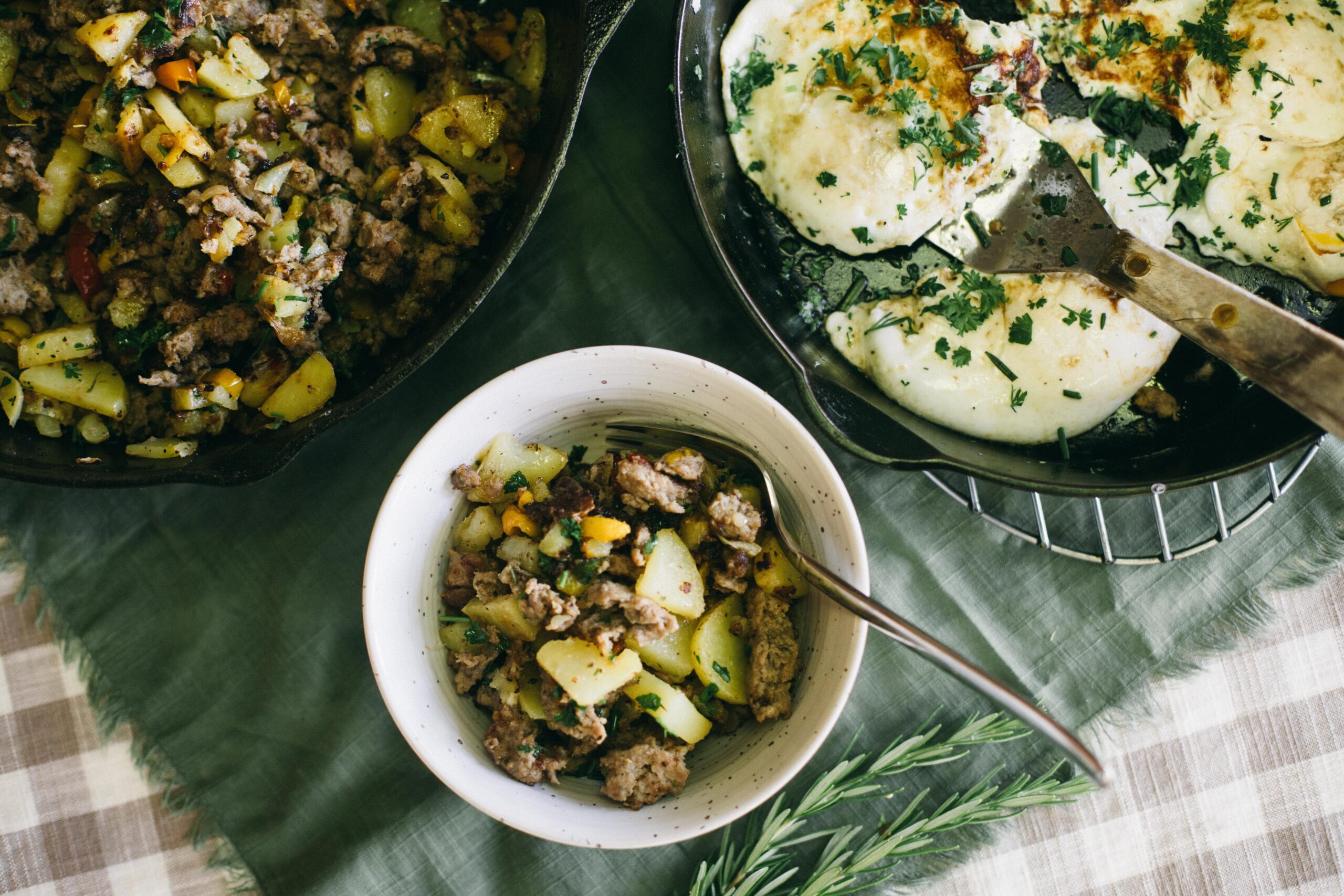 Image of a bowl full of Breakfast Skillet and two cast iron pans with the skillet recipe and fried eggs