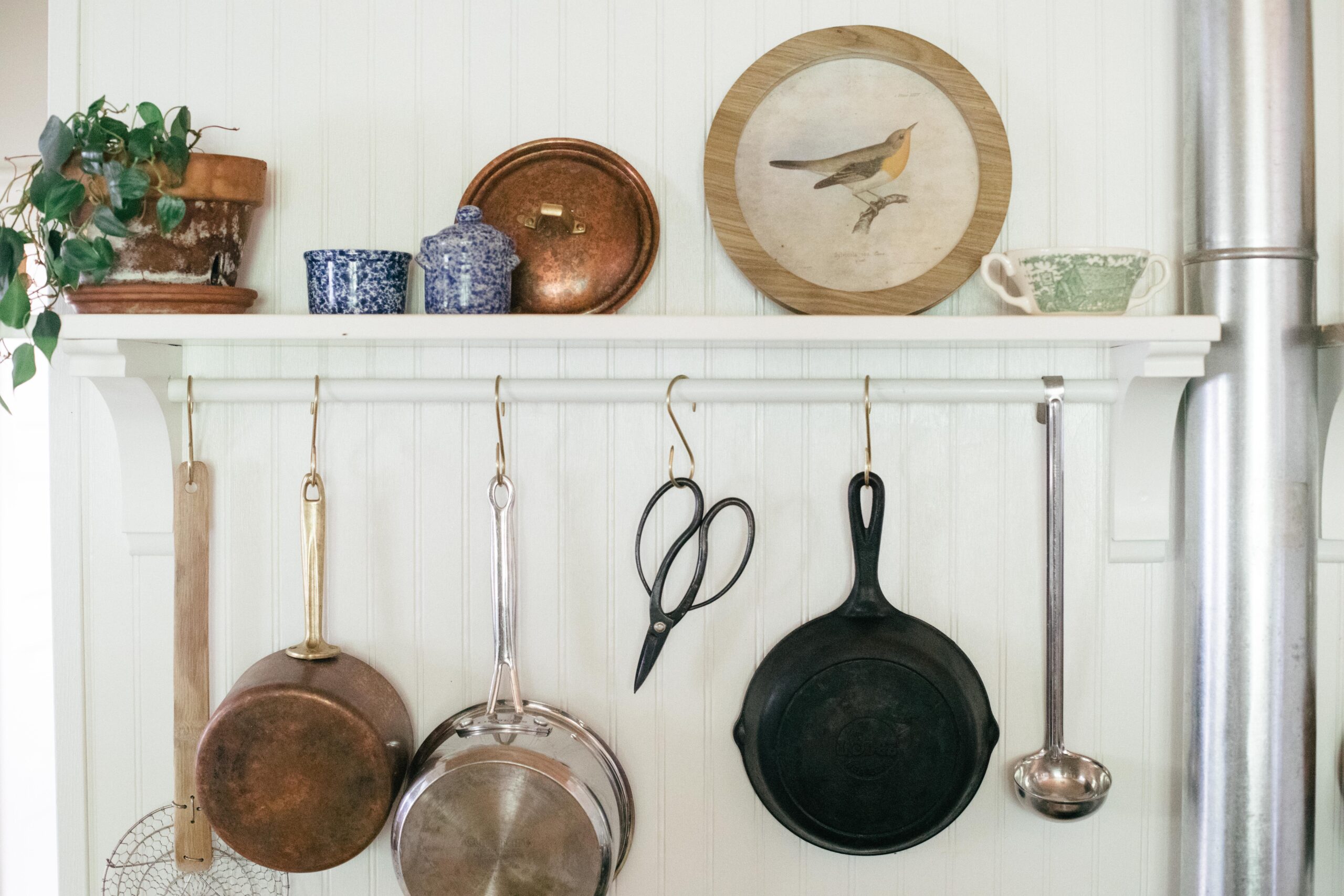 Photo of a vintage stove with brass pot racks and copper pots in an unfitted kitchen