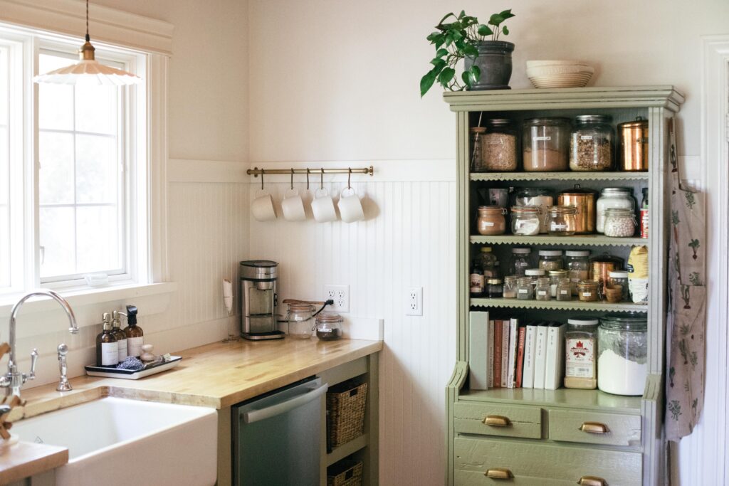 Photo of a white unfitted kitchen with a green cabinet and butcher block counters