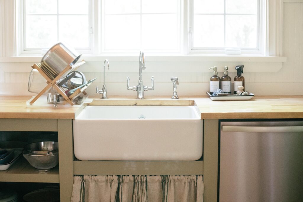 Image of a farmhouse sink in an unfitted kitchen with a chrome faucet and white beadboard