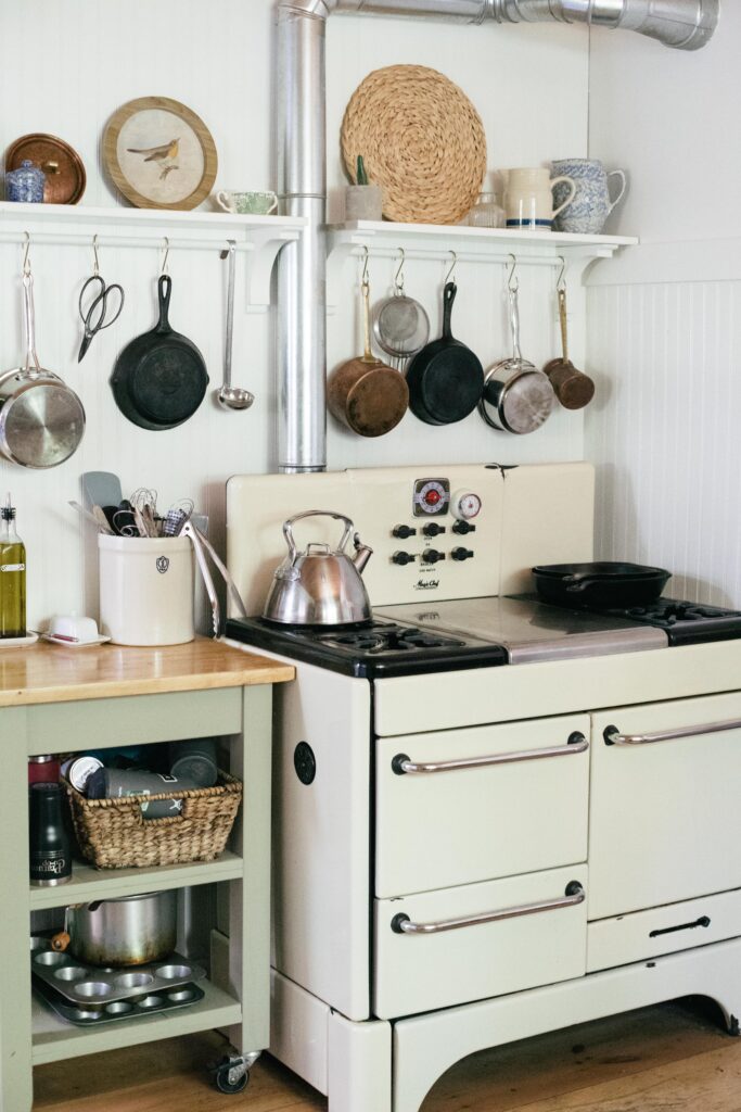 Image of a vintage stove in an unfitted kitchen with copper pots and kitchen carts