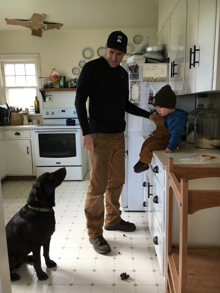 Image of a man, boy and dog in a farmhouse white kitchen