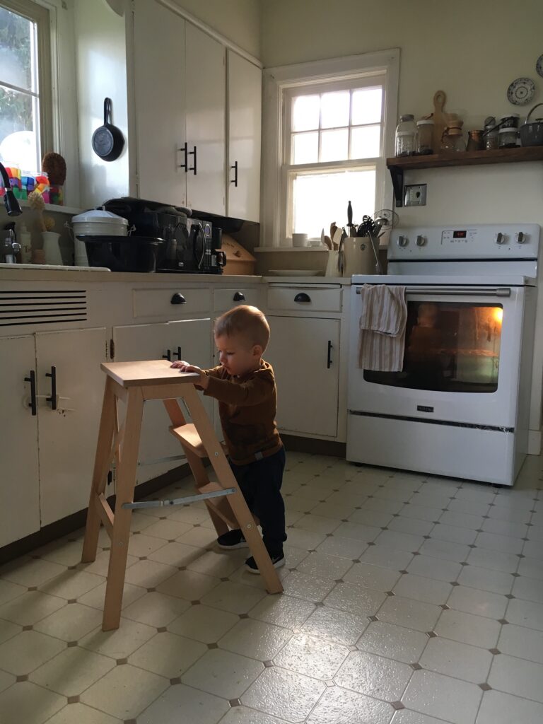 Image of a little boy on a stool in a farmhouse white kitchen