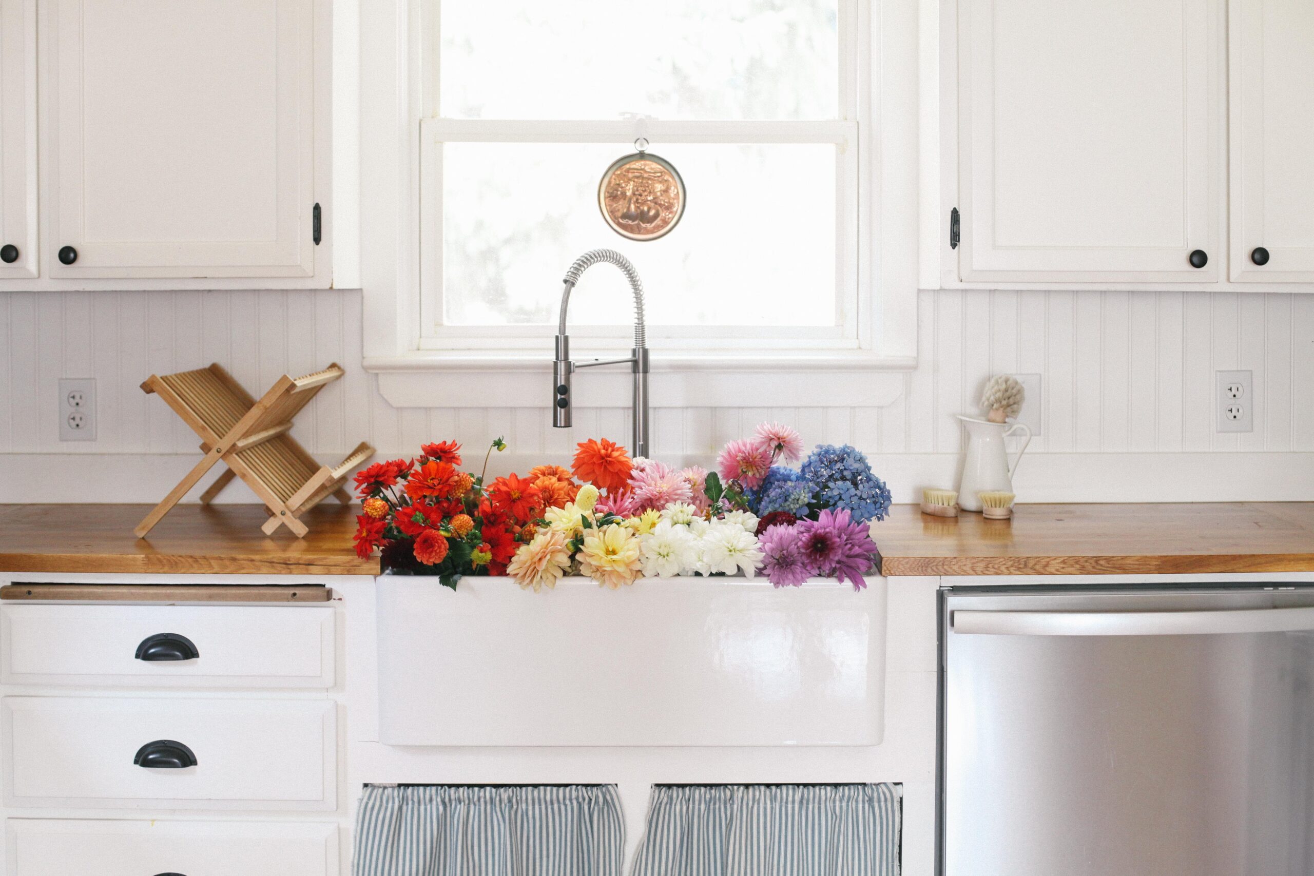 Image of a farm sink full of dahlias in a farmhouse white kitchen