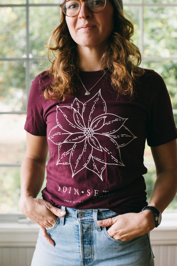 Image of a woman wearing a Potager Online Poinsettia Gardening Tee