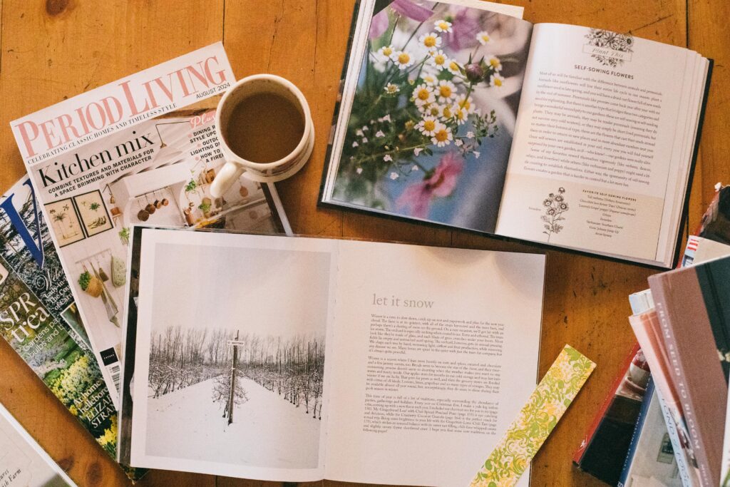 Image of books laid out on the floor with hot cocoa to read during winter