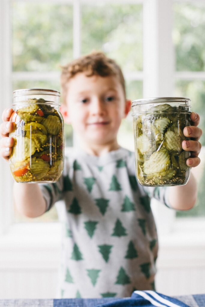 Image of a boy holding jars of preserves from the garden, home canned pickles